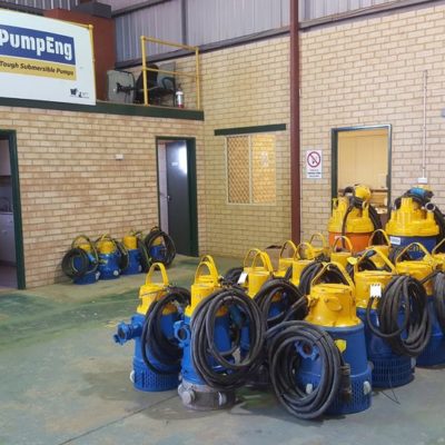 Multiple submersible underground mine dewatering pumps by PumpEng sitting on a warehouse floor