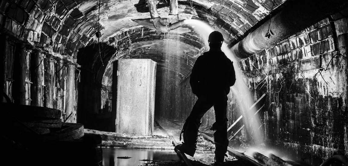 Silhouette of a man standing in an underground mine while water is being pumped