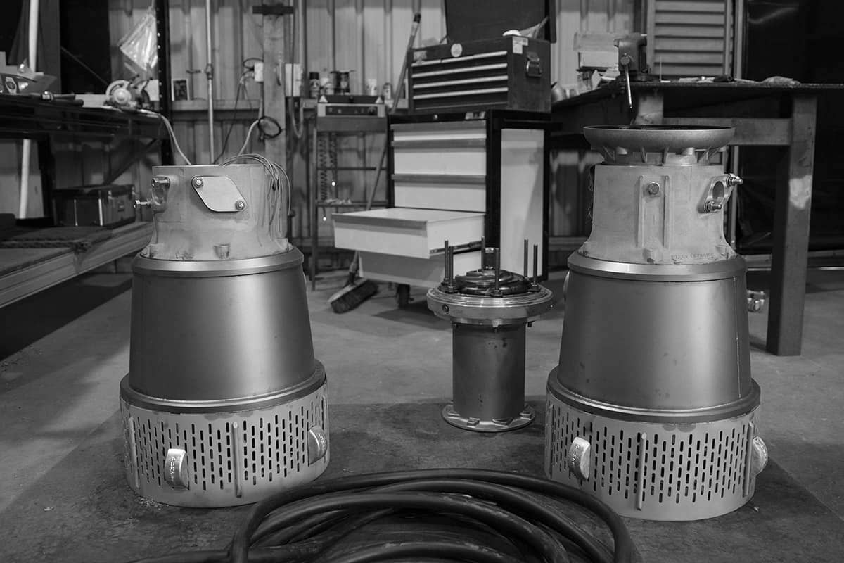 Two underground mine dewatering pumps sitting in a workshop having parts being replaced