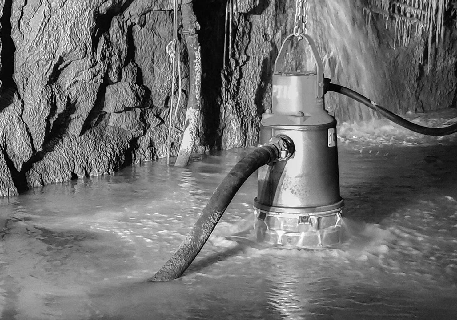 An underground mine dewatering pump pumping water while semi-submersed in an underground mine