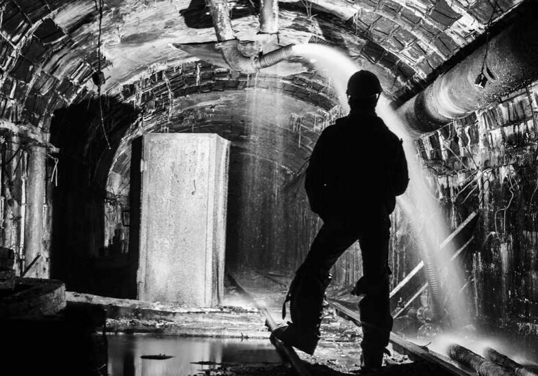 Silhouette of a man standing in an underground mine while water is being pumped