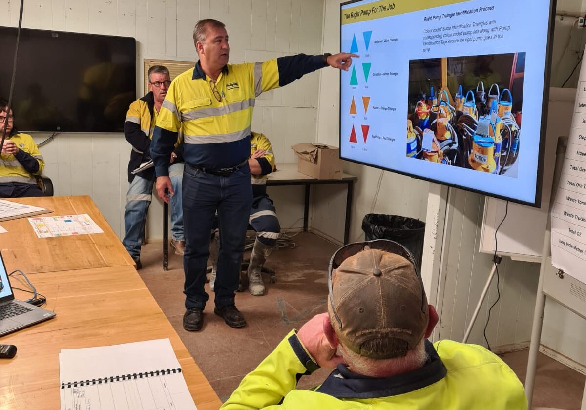 PumpEng worker demonstrating the PumpEng Triangle Guide for mining pump identification