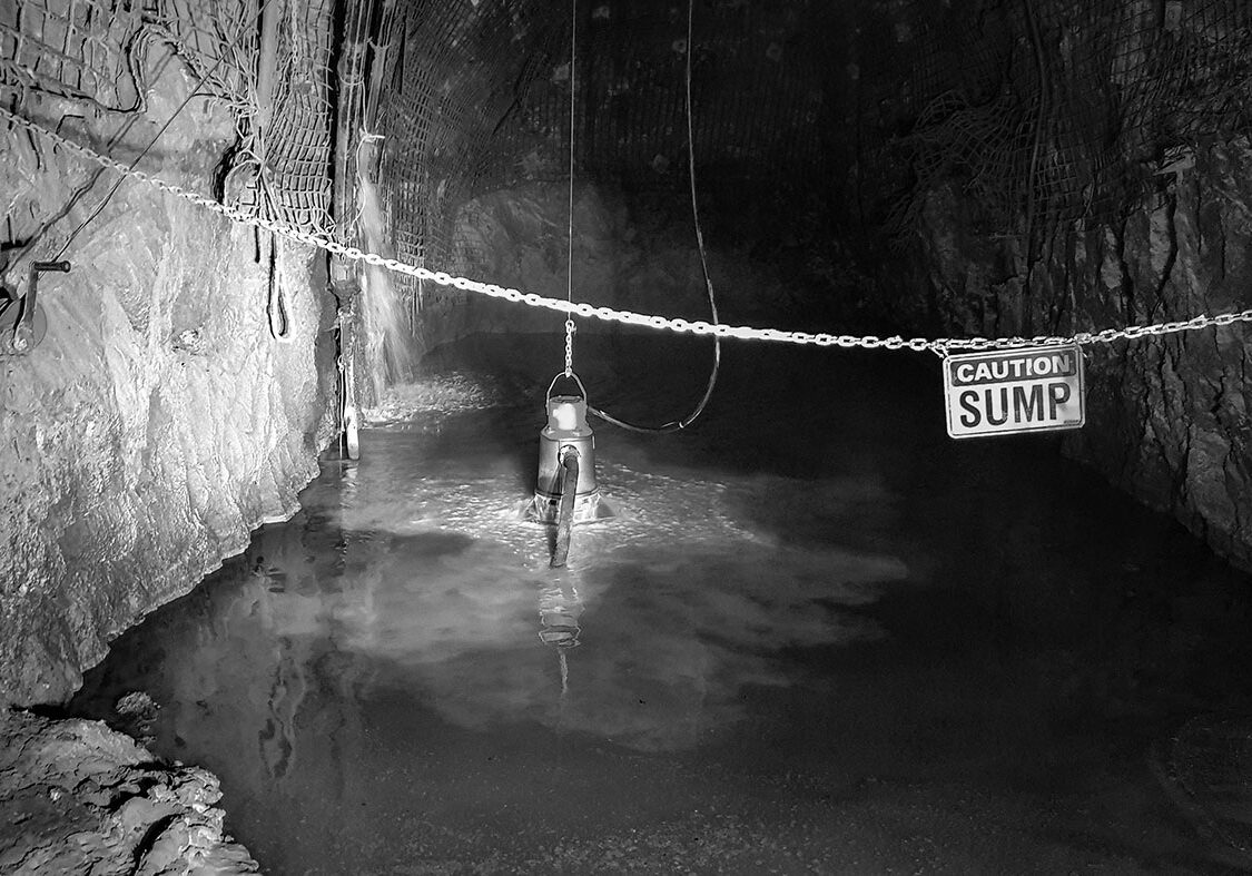 An underground mine dewatering pump pumping water while submersed in an underground mine